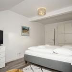 Schlafzimmer mit Bett, Kleiderschrank, Fernseher und Nachttisch.