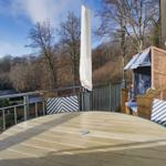 Terrasse mit Tisch, Stühlen und Strandkorb. Blick auf Wald und Himmel.