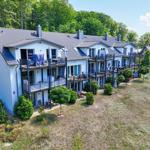 Ferienhaus mit Balkonen und Garten. Umgeben von Bäumen und Grünflächen.