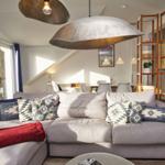 Großer Wohnbereich mit Sofa, Deckenleuchten und Blick auf Terrasse.