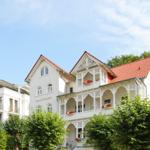 Haus Eintracht mit weißen Fassaden, rotem Dach und Balkonen mit Blumen.