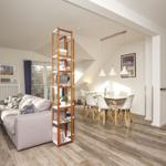 Wohn- und Essbereich mit Sofa, Tisch und Stühlen. Holzfußboden und Fenster.