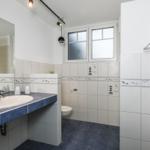 Badezimmer mit Waschbecken, Toilette und Fenster. Fliesen mit Seemotiven.