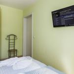 Schlafzimmer mit Bett, Kleiderständer, Schrank und Wandfernseher.