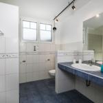 Badezimmer mit Waschbecken, Spiegel und Toilette. Fliesen mit Seestil-Motiven.