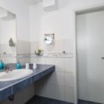 Badezimmer mit Waschbecken, Spiegel und Handtuchheizung.