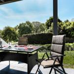 Terrasse mit Tisch und Stühlen, Blick auf grüne Landschaft und einen Turm.