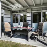 Terrasse mit Sitzgruppe, Tisch und Glashaus. Außenbereich mit Sonnenschutz.
