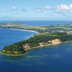 Aerial view of a coastal landscape with beaches, forests, and a small town.