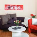 Ein Wohnzimmer mit Sofa, Sessel und Tisch. An der Wand hängt ein Bild.