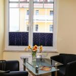 Zwei schwarze Sessel und ein Glas-Tisch stehen vor einem Fenster mit Sternen-Jalousien.