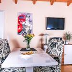 Esszimmer mit Tisch, Stühlen, Fernseher und Wandbild.