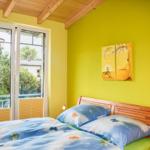 Ein Schlafzimmer mit gelben Wänden, Holzdecke und einem Bett mit Schmetterlingsmotiv.