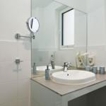 Badezimmer mit Waschbecken, Spiegel und Handtuchheizung.