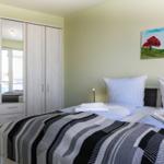 Schlafzimmer mit Doppelbett, Kleiderschrank und Wandbild.