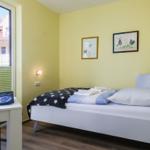 Ein Schlafzimmer mit Bett, Schreibtisch und Fenster. An den Wänden hängen Bilder.