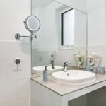 Badezimmer mit Waschbecken, Spiegel, Handtuchhalter und Fenster.