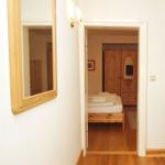 Schlafzimmer mit Holzbett und Kleiderschrank über Flur mit Spiegel und Garderobe.