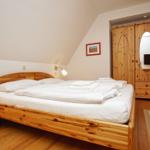 Schlafzimmer mit Holzbett, Kleiderschrank und Stehlampe.