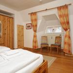 Schlafzimmer mit Holzbett, Kleiderschrank und Fenster mit Vorhängen.