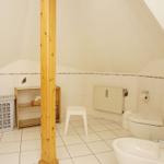 Badezimmer mit Toilette, Waschbecken und Duschbereich unter Dachschrägen.