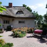 Haus mit Strohdach und Garten mit Tisch und Stühlen.