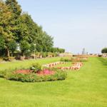 Grünflächen mit Blumenbeeten und Bäumen entlang eines Weges.