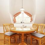 Esszimmer mit Holztisch, vier Stühlen und Bogenfenster. Fernseher und Blumen sind sichtbar.