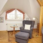 Dachgeschosszimmer mit Sessel, Fußhocker und Fenster