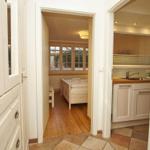 Durchgang zu Schlafzimmer und Küche mit Holzboden und weißen Möbeln.