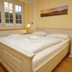 Schlafzimmer mit Doppelbett, Fenstern und Nachttisch