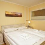 Schlafzimmer mit Doppelbett, Nachttischen und Wandbild. Fenster mit Jalousie.