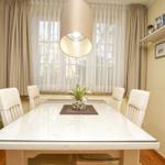 Esszimmer mit Tisch, Stühlen, Vorhängen und Deckenleuchte. Wand mit Bildern und Regal.