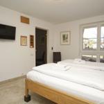 Zimmer mit Doppelbett, TV und Fensterblick auf Außenbereich.