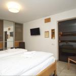 Zimmer mit Doppelbett, TV und Sitzgelegenheit. Sauna ist im Anschluss.
