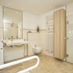 Badezimmer mit Dusche, Waschmaschine und Spiegelschrank.