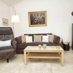 Wohnzimmer mit Sofa, Sessel, Tisch und Kaminofen.