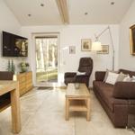 Wohn- und Essbereich mit Sofa, Sessel, Couchtisch und TV. Durchgang zur Terrasse.