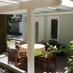 Terrasse mit Tisch, Stühlen und Sonnenschutz unter einem weißen Pavillon.