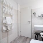 Badezimmer mit Handtuchwärmer, Waschbecken und Spiegel