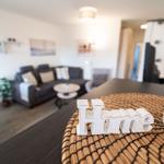 Ein Wohnzimmer mit Sofa, Tisch und Dekoration. Auf dem Tisch steht das Wort Home.