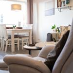 Ein Wohn- und Essbereich mit Sofa, Tisch und Stühlen sowie Fenster und Wandregal.