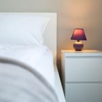 Ein Bett mit weißer Bettwäsche und einem Nachttisch mit einer Lampe.