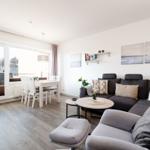 Wohn- und Essbereich mit Sofa, Esstisch und Balkontür.