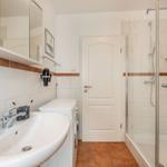 Badezimmer mit Dusche, Waschmaschine und Spiegelschrank.