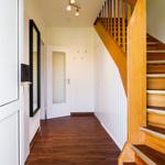 Flur mit Holztreppe, dunklem Parkett und moderner Deckenbeleuchtung.