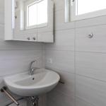 Badezimmer mit Waschbecken, Spiegelschrank und Fenster.