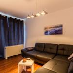 Wohnzimmer mit Leder Sofa, Tisch, Wandbild und Vorhängen.
