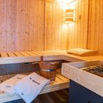 Sauna mit Holzbank, Badekorb und Handtüchern.
