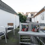 Terrasse mit Sitzgelegenheit, Tisch und Stühlen. Hintergrund: weiße Wände und Dächer.